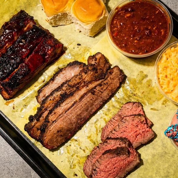 Barbecue platter with ribs, brisket, sliced beef, baked beans, mac and cheese, and ice cream.